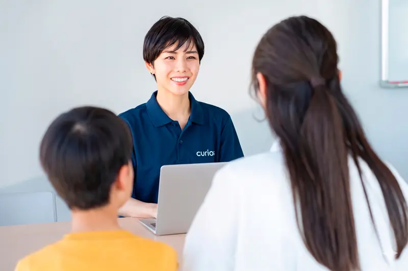 無料体験を終えた子どもの様子を見てプランを提案するスタッフと説明を受ける保護者
